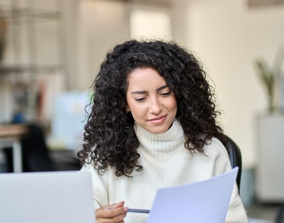 Latina woman taking notes at computer